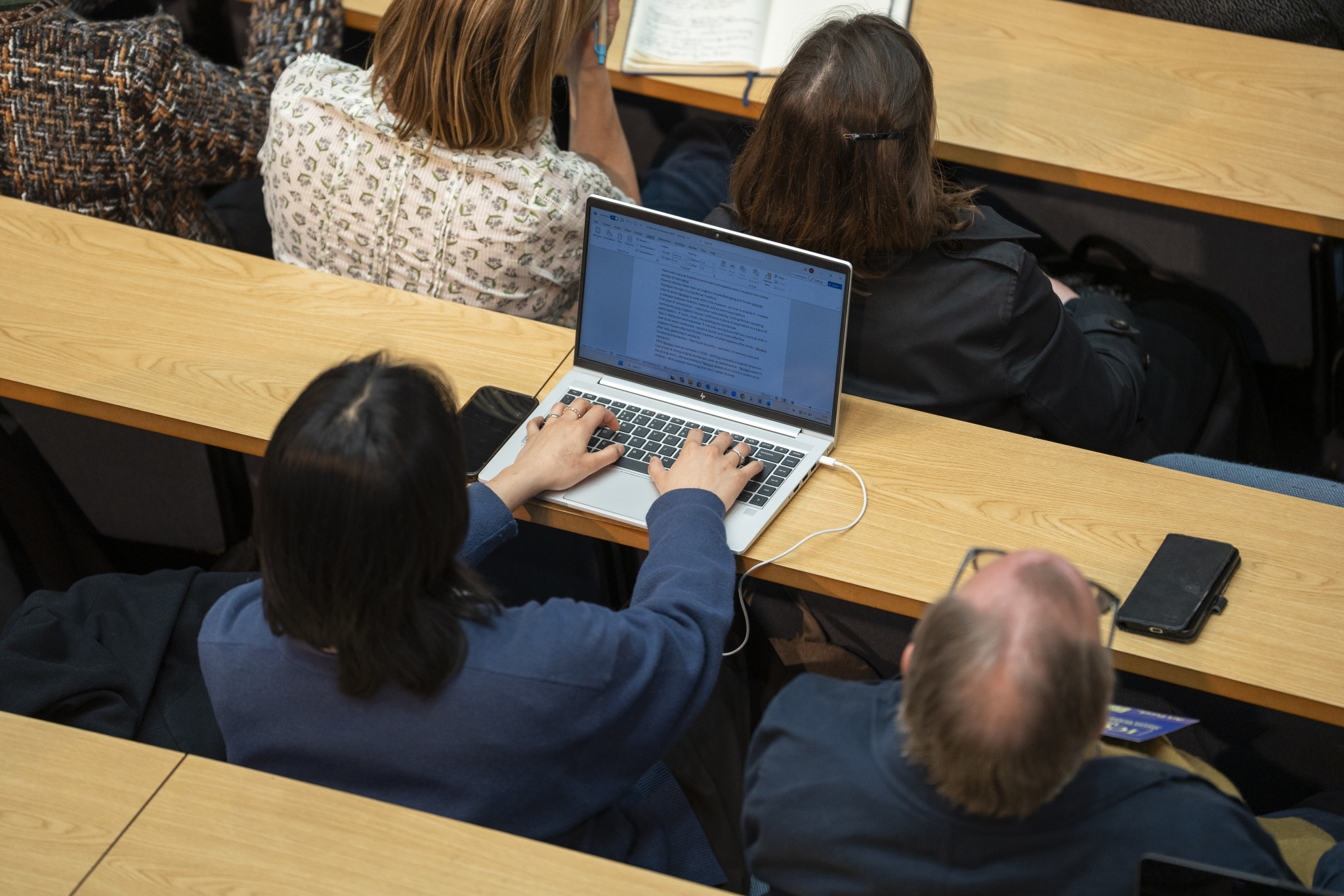 Overhead shot of person working on laptop in lecture theatre